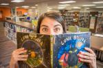 A library staff member hides behind children's book "Luna Oscura" in the Youth Department at the Main Library.