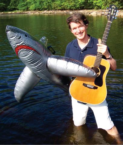 Musician Tom Sieling holding guitar and inflatable shark.