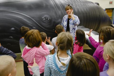 An instructor talking to children in front of Nile, a life-sized inflatable whale.